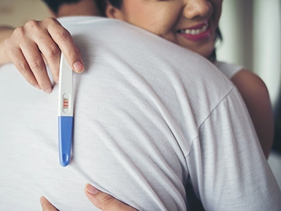 زوجان سعيدان يبتسمان بعد نتيجة اختبار الحمل الإيجابية